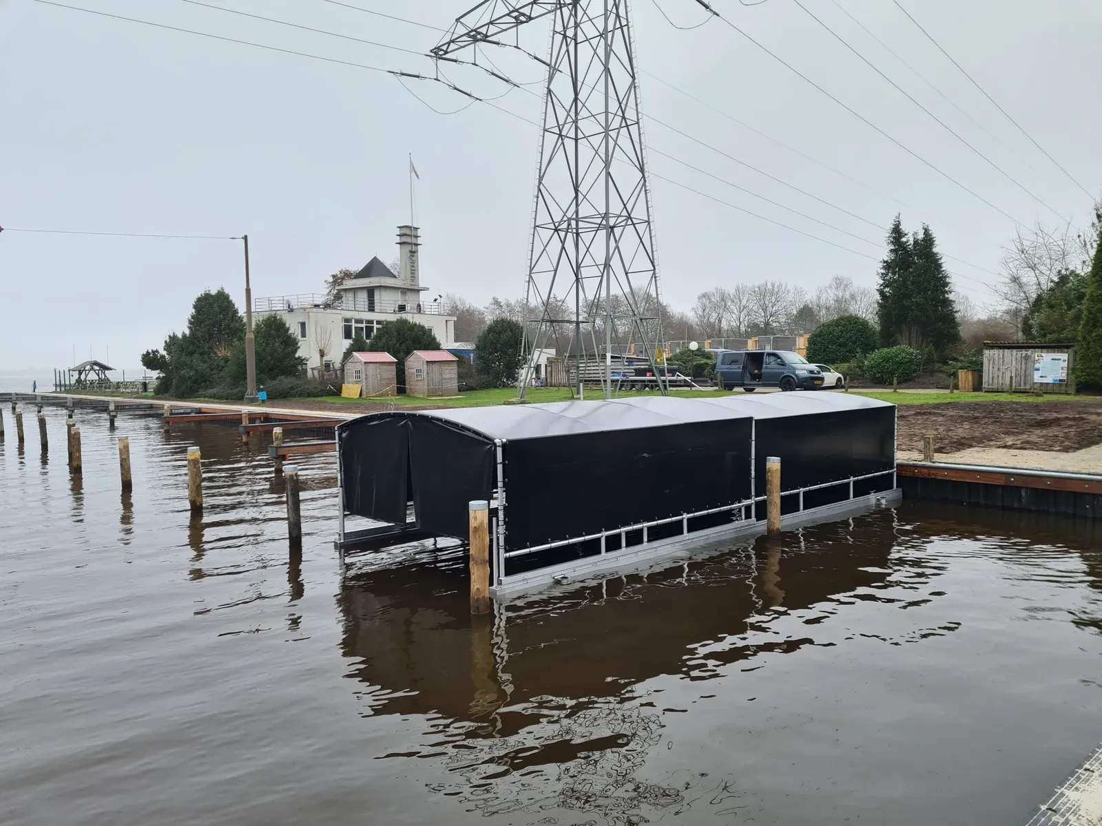 Zwarte bootoverkapping aan de oever van een plas