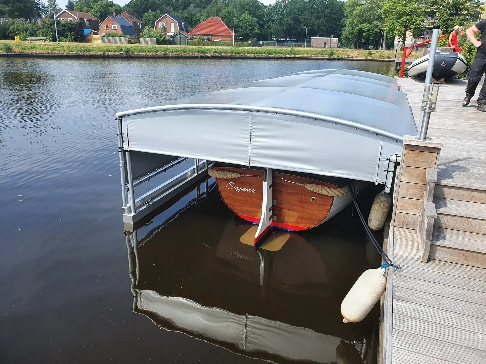 Houten sloep onder een geopende bootoverkapping aan een steiger